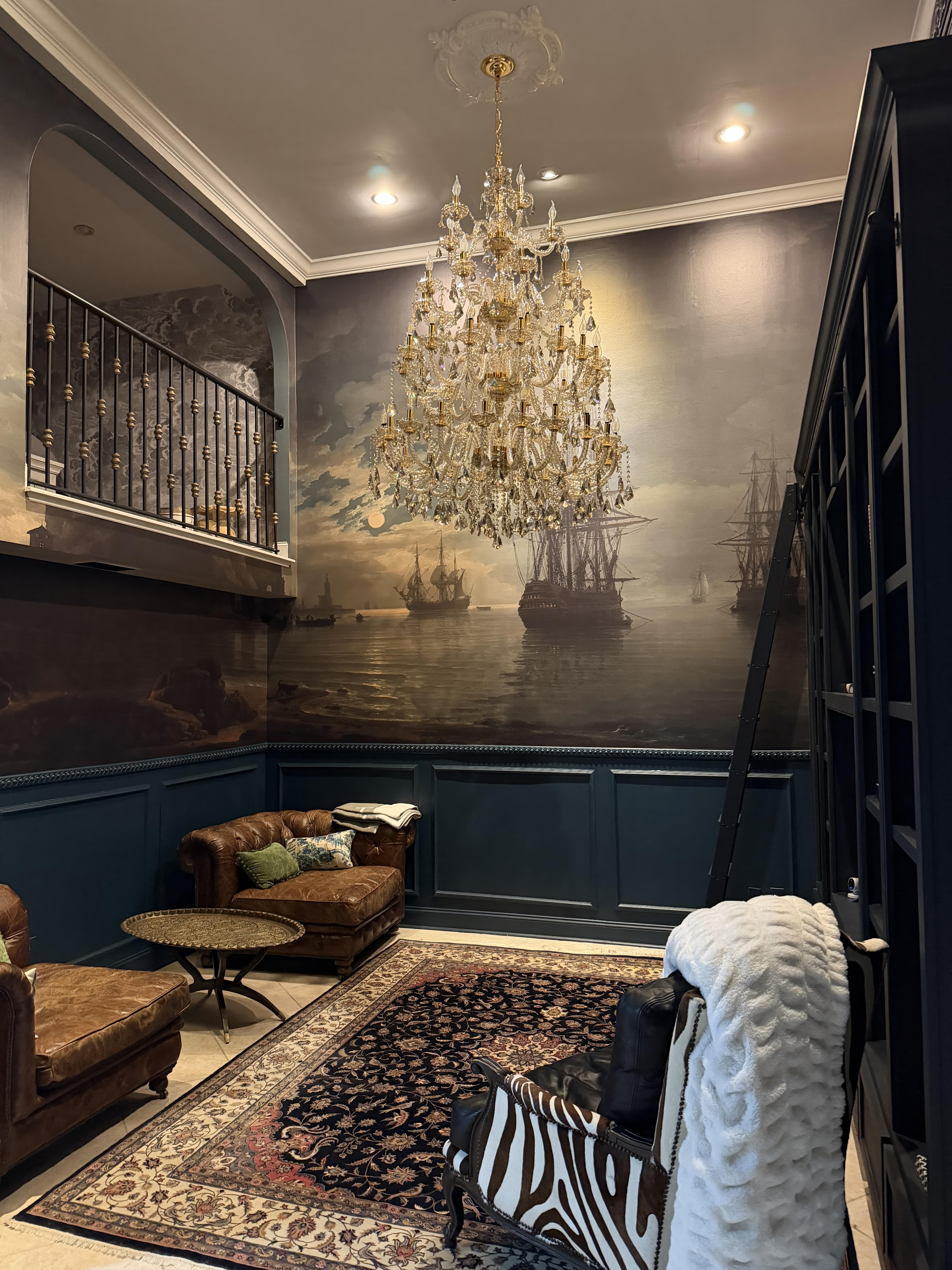 Finished room with a 15-foot Fine & Dandy mural, Farrow & Ball paneling, and a crystal chandelier on King Street in Charleston