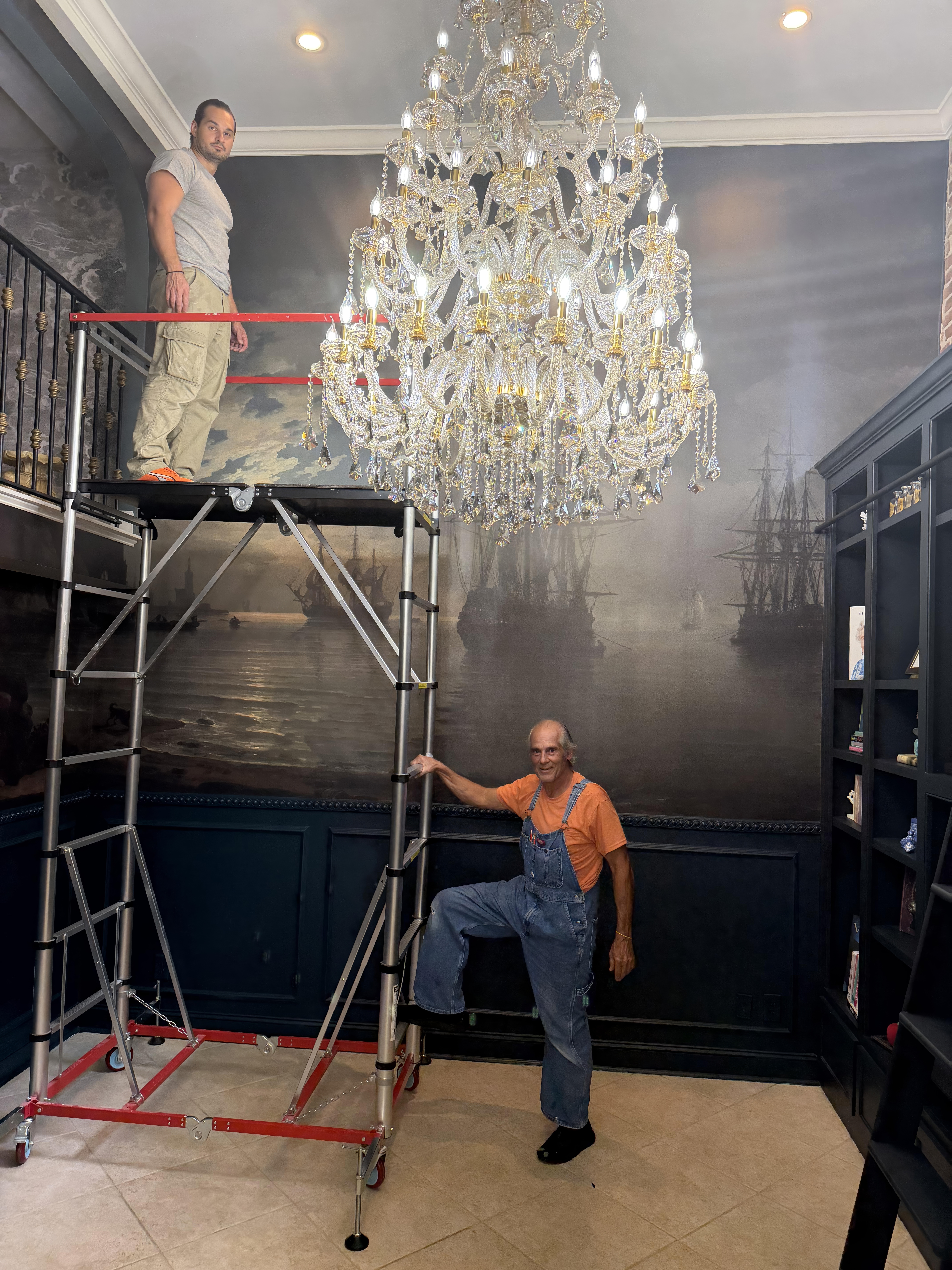 Constantine Kazameas on a scaffold and George Kazameas below positioning the mural